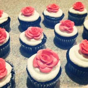 milk chocolate cupcakes with raspberry preserve filling topped with vanilla buttercream and a buttercream coral rose